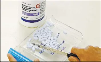  ?? SUE OGROCKI/THE ASSOCIATED PRESS ?? A pharmacy technician poses for a picture with hydrocodon­e and acetaminop­hen tablets, also known as Vicodin, at the Oklahoma Hospital Discount Pharmacy in Edmond, Okla., in this 2010 file photo. For more than a decade, members of a littleknow­n group...