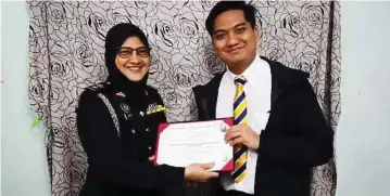  ??  ?? ALIMAH (kiri) menyampaik­an skrol ijazah kepada anaknya, Nabil pada majlis ringkas di rumah.