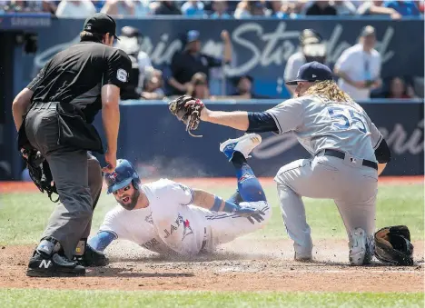  ?? FRED THORNHILL/THE CANADIAN PRESS ?? Home plate umpire Ryan Additon watches as Kevin Pillar slides safely into home under the tag of Tampa Bay Rays pitcher Ryne Stanek in the sixth inning of a 2-1 Blue Jays victory in Toronto on Sunday. The dramatic win allowed the Jays to avoid being swept.