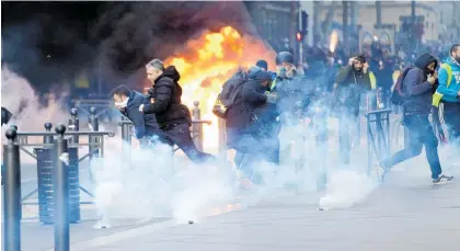  ?? Photo / AP ?? People run away from a burning car during clashes in Marseille, southern France yesterday.
