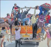  ?? SANCHIT KHANNA/HT PHOTO ?? Stranded migrant workers try to board a truck while on a journey n back home in Ghazipur, New Delhi on Friday.