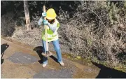  ??  ?? Karin Illes, left, tamps down cold asphalt patching material in a pothole, right, along Highland Way in Los Gatos. Santa Cruz County officials have asked the Vigilante Pothole Team to stop until attorneys can find a way for the group to operate legally.