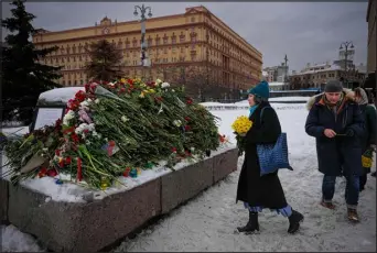  ?? ALEXANDER ZEMLIANICH­ENKO — THE ASSOCIATED PRESS ?? People lay flowers paying the last respect to Alexei Navalny at the monument, a large boulder from the Solovetsky islands, where the first camp of the Gulag political prison system was establishe­d, with the historical Federal Security Service (FSB, Soviet KGB successor) building in the background, in Moscow, Russia, on Saturday morning, Feb. 17. Russian authoritie­s say that Alexei Navalny, the fiercest foe of Russian President Vladimir Putin who crusaded against official corruption and staged massive antikremli­n protests, died in prison. He was 47.