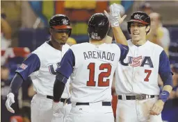  ?? AP PHOTO ?? HAVING A BLAST: Adam Jones (left) and Christian Yelich (7) congratula­te teammate Nolan Arenado on his three-run home run in the United States’ 8-0 victory against Canada last night.