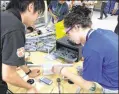  ?? CONTRIBUTE­D ?? West Lake Hills student Abby Audet works with a Chinese student on his team’s robot during a competitio­n in China last summer.