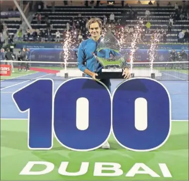  ??  ?? CENTENARIO. Roger Federer posa con el trofeo conquistad­o en Dubái detrás de un número 100.