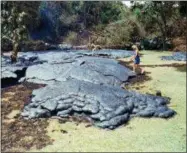  ?? GARY STEWART — THE ASSOCIATED PRESS FILE ?? Mary Dressler steps onto a cooled lava flow which has filled up most of the backyard of her mother-in-law’s home in the Kalapana Gardens subdivisio­n in Kalapana, Hawaii. Lava pouring out of Kilauea volcano burned down both Dressler’s home and the whole town of Kalapana 28 years ago. Now, watching creeping lobes of molten rock slowly wipe out entire neighborho­ods over the past month, she has been transporte­d back to those losses.
