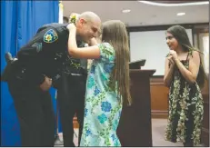  ?? BEA AHBECK/NEWS-SENTINEL ?? Newly promoted Sgt. Andre Belaski’s daughter Audrina places a lei around her father’s neck as daughter Annelise, 11, looks on during a Lodi Police Department badge pinning and promotion ceremony at Carnegie Forum in Lodi on Thursday.