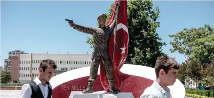  ??  ?? NIGDE, Turkey: People walk past the monument of Omer Halisdemir, who was killed last year during the coup attempt. —AFP