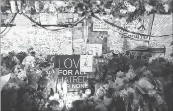  ?? CP PHOTO ?? Flowers, notes and candles are piled high at a vigil on Yonge Street in Toronto.