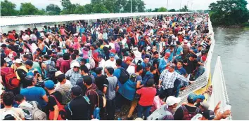 ?? AFP ?? Honduran migrants taking part in a caravan to the US wait to cross to Mexico, in Ciudad Tecun Uman, Guatemala. Thousands of migrants forced their way through Guatemala’s northweste­rn border and flooded onto a bridge leading to Mexico, where riot police battled them.