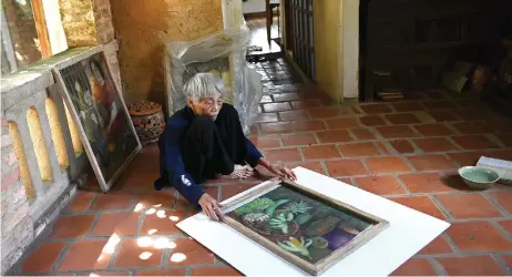  ??  ?? Bich holding a painting inside her house in Bac Ninh province, east of Hanoi.