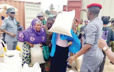  ?? PHOTO: Benedict Uwalaka ?? Lagos residents with bags of rice bought as the Nigeria Customs Service begins sale of seized food items at the service’s Zone A headquarte­rs in Yaba, Lagos State yesterday