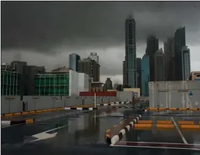  ?? (AP/Jon Gambrell) ?? Storm clouds cover up the tops of buildings in the Dubai Marina as rain falls on a parking lot that stands empty over the coronaviru­s pandemic in Dubai, United Arab Emirates, on Wednesday. Middle East economies, already wracked by high numbers of unemployed youth, unrest, conflict and large numbers of refugees, will sink into a recession this year sparked by the double shock of the coronaviru­s outbreak and low oil prices, the Internatio­nal Monetary Fund said Wednesday.