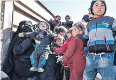  ??  ?? Members of the Syrian Democratic Forces, right, prepare to move from a house on the edge of the last pocket of territory controlled by Isil near the village of Baghuz, Deir Ezzor province. Left, families who fled the jihadists wait in a lorry to be taken to a camp for displaced people. Many are cold and hungry, others have been injured in fierce fighting and air strikes in the area