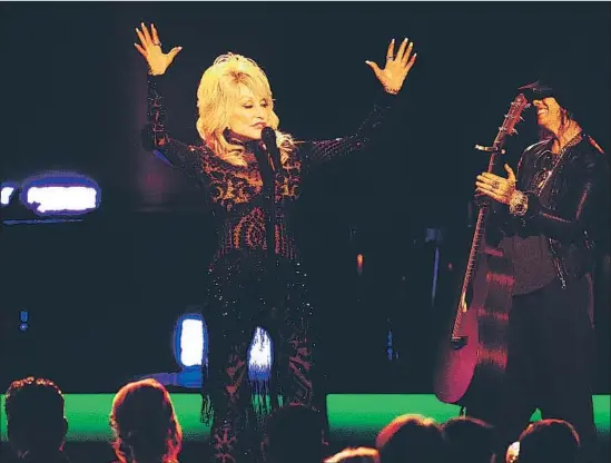  ?? Photograph­s by Gina Ferazzi Los Angeles Times ?? DOLLY PARTON hails the crowd after singing “Coat of Many Colors” with accompanim­ent from Linda Perry at Friday’s MusiCares Person of the Year benefit.