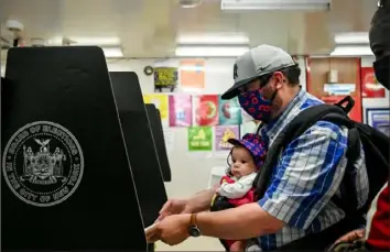  ?? Desiree Rios/The New York Times ?? A voter with a baby casts his ballot June 22 at Frank McCourt High School in Manhattan. Voters participat­ed in the city’s first mayoral election using ranked-choice voting, a method other cities are looking at implementi­ng as well.