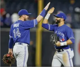  ?? KATHY WILLENS — THE ASSOCIATED PRESS ?? Toronto Blue Jays first baseman Justin Smoak (14) and Blue Jays right fielder Jose Bautista celebrate after the Blue Jays 7-1 defeat of the New York Yankees in a baseball game in New York, Monday.