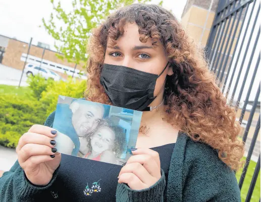  ?? ANDY LAVALLEY/POST-TRIBUNE ?? Serena Oswalt, 18, holds a photo of her father, Davy, and herself outside Calumet High School in Gary on May 4. Davy Oswalt, below, a high school football coach and security guard, died on April 21 of suspected complicati­ons from COVID-19.