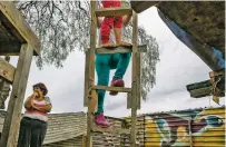  ?? MAURICIO LIMA/NEW YORK TIMES ?? Esther Arias with her grandchild­ren Sol, 9, and Damian, 5, on the back patio of their home, which abuts the U.S. border wall in Tijuana, Mexico.