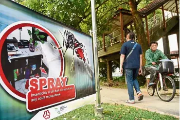  ??  ?? Mozzie danger: Residents passing by a banner against the spread of Aedes mosquitoes, carriers for the Zika virus, at a residentia­l block in Aljunied Crescent. — AFP