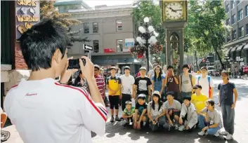  ?? KIM STALLKNECH­T/ PNG PHOTO ?? Asian tourists pose for pictures at the steam clock in Gastown. More Chinese are visiting the city.