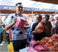  ?? — Bernama photo ?? Muhamad Akmal (left) shows a Madani Combo set containing flour, sugar, cooking oil and others, available for RM10 at the Semarak Syawal Agro Madani Sales event.