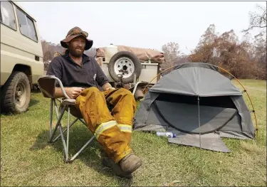  ?? RICK RYCROFT — THE ASSOCIATED PRESS ?? Volunteer firefighte­r Ash Graham camps on the lawn near the fire station at Nerrigunda­h, Australia, Monday since losing his house and his dog when a wildfire ripped through the town on New Year’s Eve. The tiny village of Nerrigunda­h in New South Wales has been among the hardest hit by Australia’s devastatin­g wildfires, with about two thirds of the homes destroyed and a 71-year-old man killed.