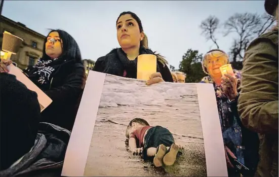  ?? CHRIS HOPKINS / GETTY ?? Manifestan­tes en Melbourne (Australia) sostienen la terrible fotografía de Aylan Kurdi, el niño sirio de tres años ahogado en una playa turca
