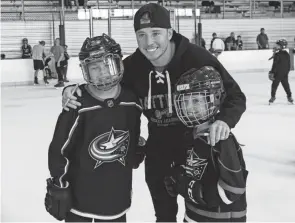  ?? PHOTOS BY NICOLAS GALINDO/THE COLUMBUS DISPATCH ?? Recently traded Blue Jackets winger Cam Atkinson poses for a photo with Sofie, 10, and Lily Laforche, 8, during a send off party at the Ohiohealth Ice Haus in Columbus on Saturday. Fans were able to ice skate and meet Atkinson for photos and autographs during the event.