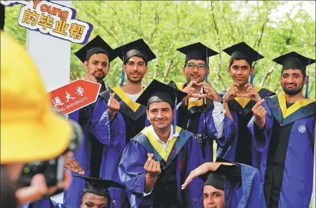  ?? LIU YING / XINHUA ?? Foreign graduates of Shanghai Jiao Tong University take a group photo on campus in July last year.