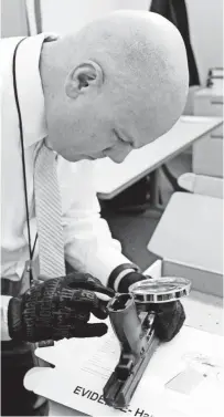  ?? JOHN SCHULTZ/ QUAD CITY TIMES VIA AP ?? Brian Morel, an ATF Task Force officer, uses a magnifying glass to read a gun’s serial number at his desk in the Davenport (Iowa) Police station. He then can input it into the National Tracing Center, the ATF's online database that lists all guns sold...