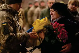  ?? ?? Tetiana Hurieieva, the mother of Volodymyr Hurieiev, a Ukrainian soldier killed in the Bakhmut area, receives the flag that draped his coffin, during the funeral in Boryspil, Ukraine, Saturday, March 4, 2023. Pressure from Russian forces mounted Saturday on Ukrainians hunkered down in Bakhmut, as residents attempted to flee with help from troops who Western analysts say may be preparing to withdraw from the key eastern stronghold. (AP Photo/Vadim Ghirda)