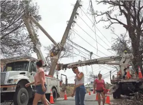  ??  ?? A utility crew works to repair toppled power lines in Corozal, Puerto Rico, after Hurricane Maria tore through the island. JOE RAEDLE/GETTY IMAGES