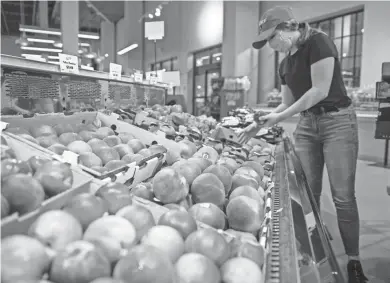  ?? JULIA MARTINS DE SA / MILWAUKEE JOURNAL SENTINEL ?? Anna Schapekahm restocks peaches at Sendik’s Food Market at the Corners of Brookfield on July 7. The seasonal produce is turning up in more and more varied dishes.