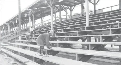  ??  ?? Workers sanding the bleacher stands on Monday afternoon