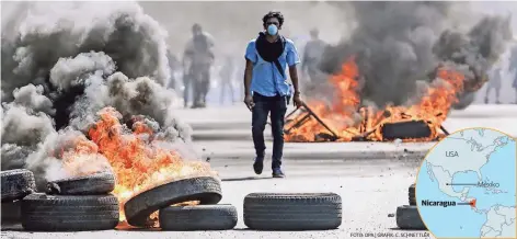  ?? FOTO: DPA | GRAFIK: C. SCHNETTLER ?? Ein maskierter Demonstran­t läuft zwischen brennenden Barrikaden in Nicaraguas Hauptstadt Managua.