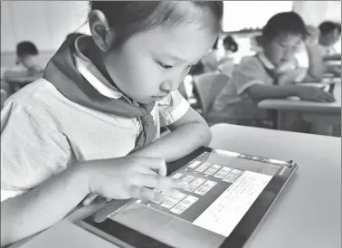  ?? GE YINIAN / FOR CHINA DAILY ?? First graders at Shushan Elementary School in Hefei, Anhui province, take their final exams of the semester on Wednesday using tablet computers instead of paper. The tablets are equipped with specialize­d software. Answers to multiple choice questions...