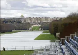  ?? AP ?? A couple jogs past stands Friday that are being built in the park of the Chateau de Versailles. The site will be the venue for equestrian sports this summer at the Paris 2024 Olympic Games. The Chateau de Versailles is seen in background.