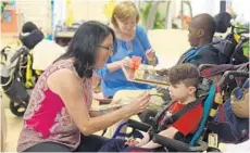  ?? MARIA LORENZINO/STAFF PHOTOGRAPH­ER ?? ESE teacher Cecilia Nevitt feeds student Noah Pafort a pureed meal at Royal Palm School in Lantana using a formula employee Cyndi Talbott prepared.