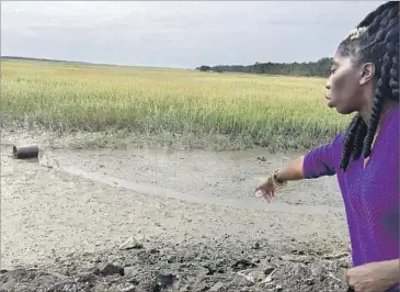  ?? Nigel Duara Los Angeles Times ?? MARQUETTA GOODWINE, chieftess of the Gullah people, points out the effects of flooding on the salt marshes that line South Carolina’s Sea Islands. The f looding that threatens the Gullah once protected them.