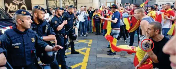  ??  ?? Skirmish: Unionist demonstrat­ors – one with a swastika tattoo on his hand, circled – face police as protests in Catalonian capital Barcelona turn violent yesterday