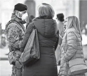  ?? CLAUDIO FURLAN/AP ?? Italian soldiers wearing masks patrol Duomo square in downtown Milan, Italy, on Monday.