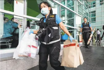  ?? Dario Pignatelli / Getty Images ?? Forensic police officers carry evidence bags outside Phramongku­tklao Hospital in Bangkok after a bombing. It was not immediatel­y clear who was responsibl­e for the attack.
