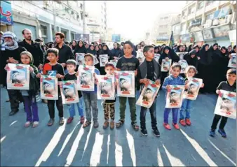  ?? ATTA KENARE / AGENCE FRANCE-PRESSE ?? Iranian boys hold images of Mohammad Taha Eghdami, 4, during a public funeral ceremony on Monday for those killed during an attack on a military parade at the weekend in the southweste­rn city of Ahvaz. At least 25 people died during the attack by four gunmen on Saturday.