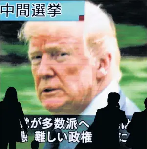  ?? EUGENE HOSHIKO/THE ASSOCIATED PRESS ?? The world was watching the U.S. midterm elections Tuesday. In Tokyo on Wednesday, people walked past a huge public TV screen showing U.S. President Donald Trump during a news program covering the pivotal event.