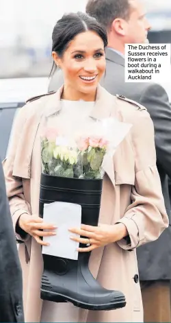  ??  ?? The Duchess of Sussex receives flowers in a boot during a walkabout in Auckland