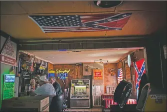  ??  ?? People sit in a bar decorated with an American flag and confederat­e flags before noon in Meridian.