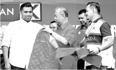  ??  ?? Muhyiddin (second, left) is putting on the PH red jacket for Muhammad Aiman (left) after the announceme­nt of PH candidate yesterday. - Bernama photo