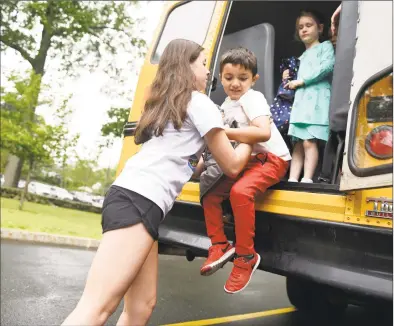  ?? Tyler Sizemore / Hearst Connecticu­t Media file photo ?? Counselor Megan Maher helps students down from the emergency exit of a school bus during a drill at the American Red Cross “Safety Town” program at Eastern Greenwich Civic Center in Old Greenwich on June 13, 2019.